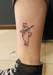 tatuaż na nodze konturowy kot z gitarą