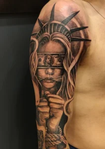 tatuaż na ramieniu statua wolności ze związanymi rękami